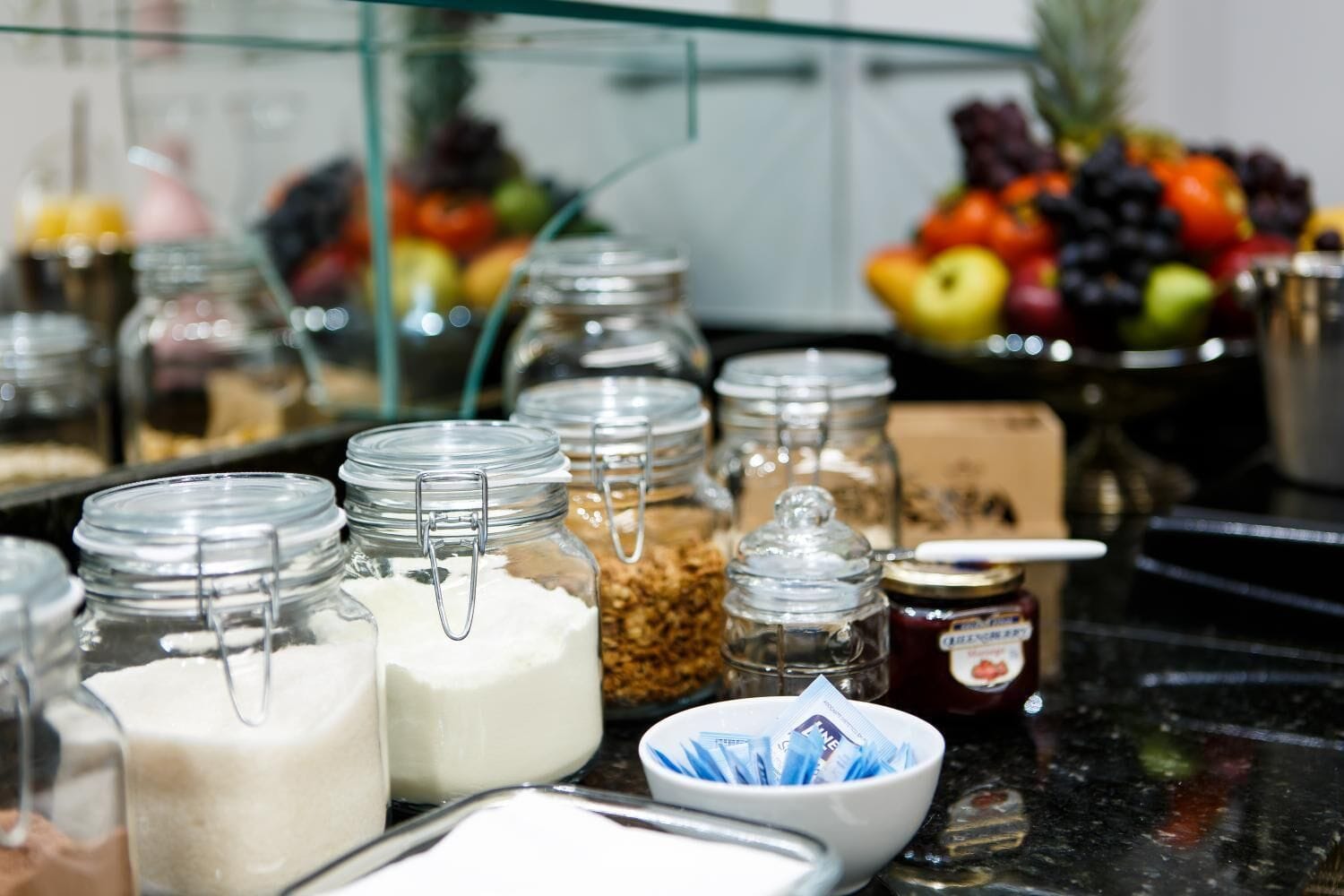 A variety of food items and condiments in glass jars on a counter.