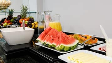A breakfast buffet with various fruits, a sink, and a pitcher of juice.