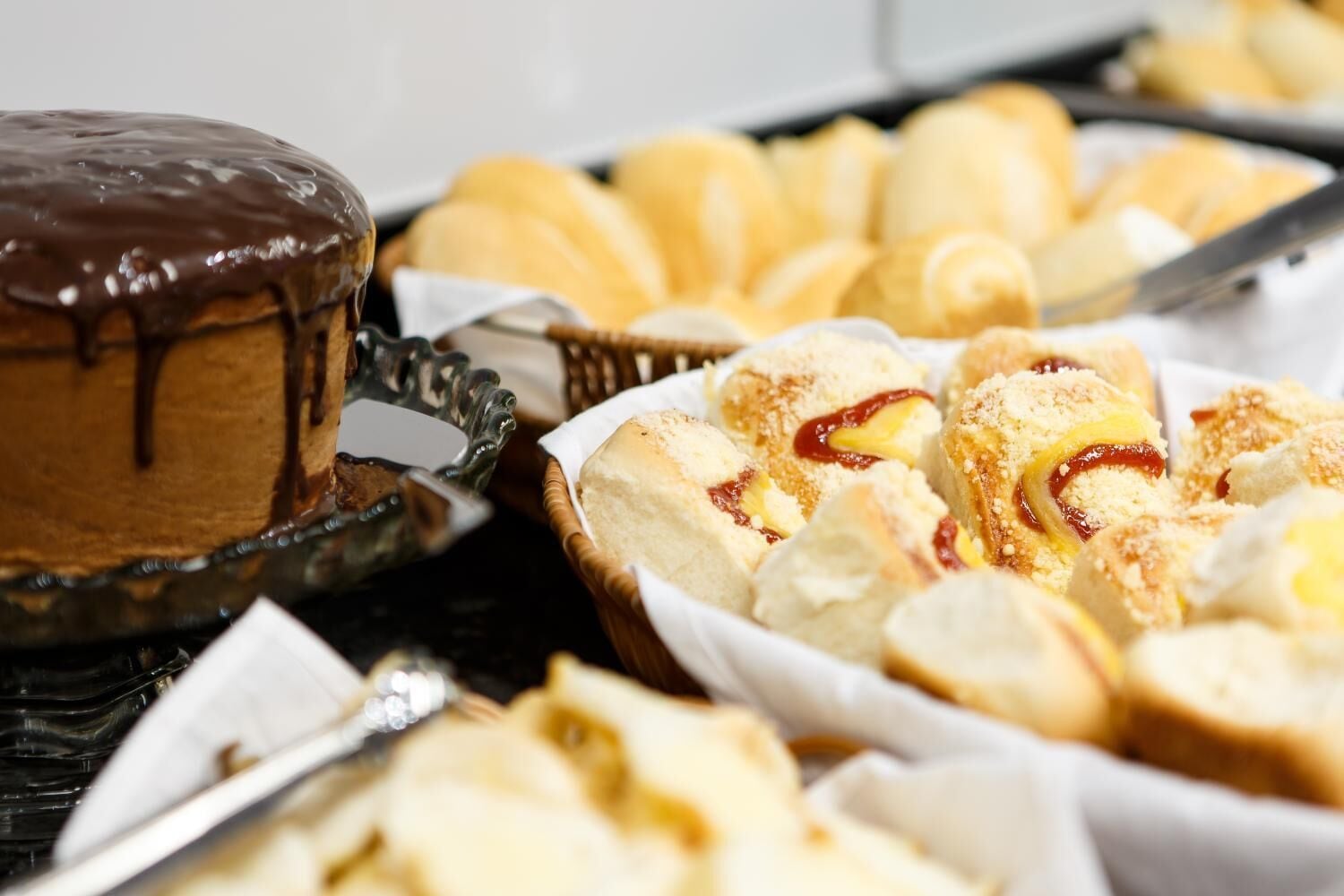 A dessert table with various pastries and a chocolate-covered cake.