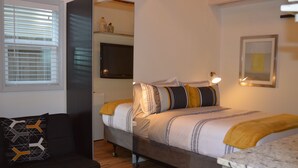 Ein modernes Schlafzimmer mit Bett, Nachttisch und einer kleinen Sitzecke mit einer Couch.