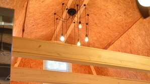 Ein kompakter Raum mit Bett, einer kleinen Couch, einem Heizkörper, einem Fenster und einer Decke mit freiliegenden Holzbalken und hängenden Lampen.