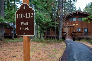 A wooden sign with the text "110-112 Wolf Creek" and a building labeled "Wolf Creek" in the background.