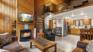 Ein geräumiger Wohnbereich mit Kamin, einer Holztreppe, einer Küche und einem Essbereich.