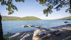 Ein Picknickplatz am Seeufer mit Bänken und einer anlegenden Mole.