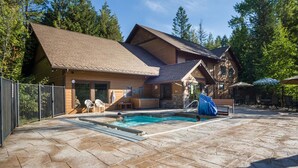Eine Lodge mit Schwimmbad, Steinterrasse und Holzfassade.