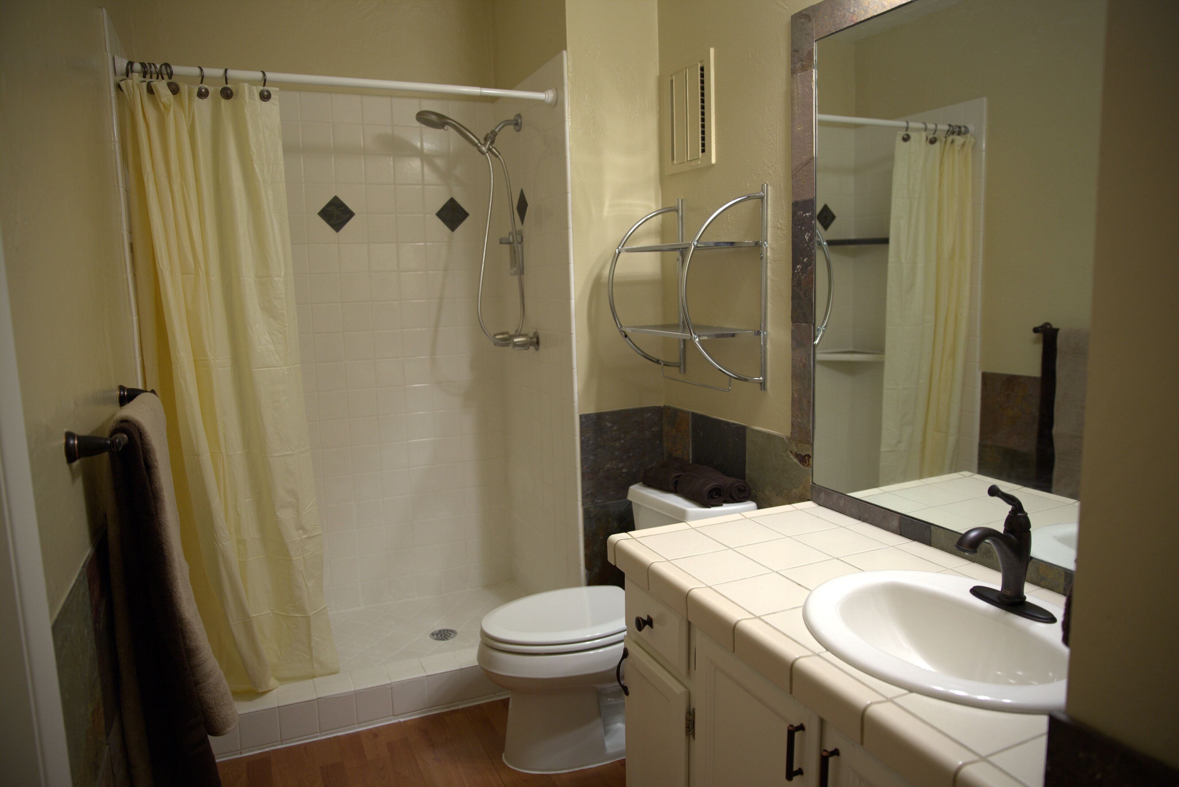 Une salle de bain équipée d’une douche, de toilettes, d’un lavabo et d’un miroir.