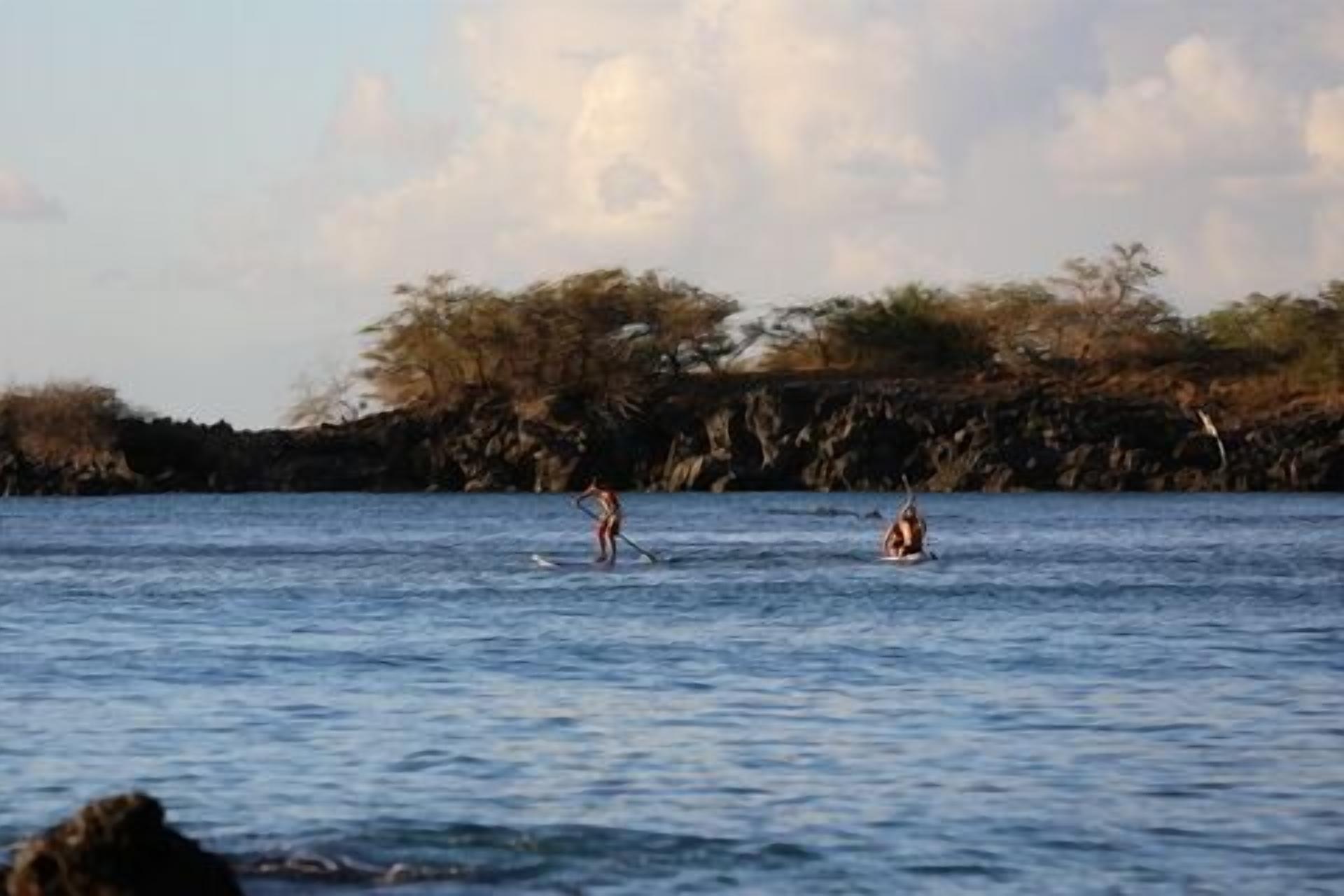 Une étendue d'eau calme sur laquelle deux personnes se déplacent en canot ou en kayak.