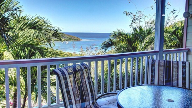 Un balcon avec vue sur l’océan, une table et des chaises.