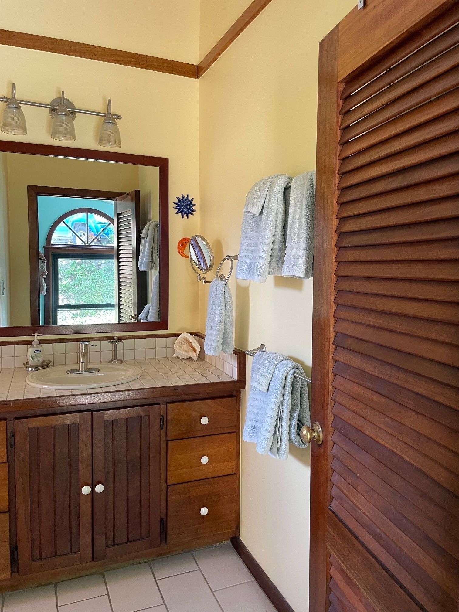 A bathroom with a wooden vanity, a sink, a mirror, and a towel rack.