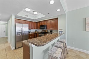 A modern kitchen with granite countertops, stainless steel appliances, and wooden cabinets. - Seawind 1703 by Liquid Life (Gulf Shores)