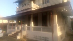 A two-story building with a porch and a staircase leading to the entrance. - Robert's Guesthouse in Port of Spain.
In the Heart of Carnival 2026 (St Clair)