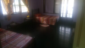 A room with two beds, a small table with a vase of flowers, and a window with curtains. - Robert's Guesthouse in Port of Spain.
In the Heart of Carnival 2026 (St Clair)