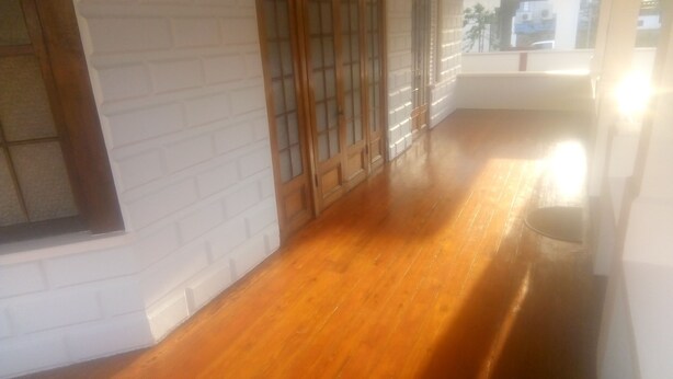 A hallway with wooden flooring, a white brick wall, and a window with a view of buildings outside. - Robert's Guesthouse in Port of Spain.
In the Heart of Carnival 2026 (St Clair)