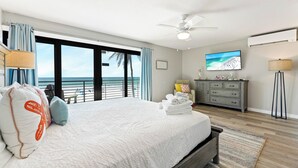 A bedroom with a large bed, a ceiling fan, a TV, a dresser, and a view of the beach. - Breathtaking 4 Bedroom/ 4 Bath Town Home Located Directly on Siesta Key Beach! (Siesta Key)