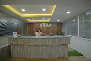 Un mostrador de recepción con detalles de madera, un reloj y un letrero que dice 'Sri Guru Krupa Reception'.