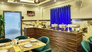 Zona de recepción de hotel con un mostrador de madera, cortinas azules y una disposición tipo buffet.