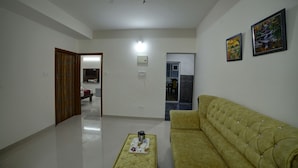 Un salón espacioso con un sofá amarillo, una mesa de centro y dos cuadros en la pared.