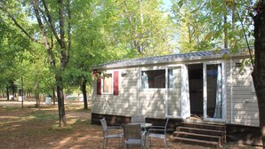 Eine kleine Holzhütte mit Veranda, Tisch und zwei Stühlen.