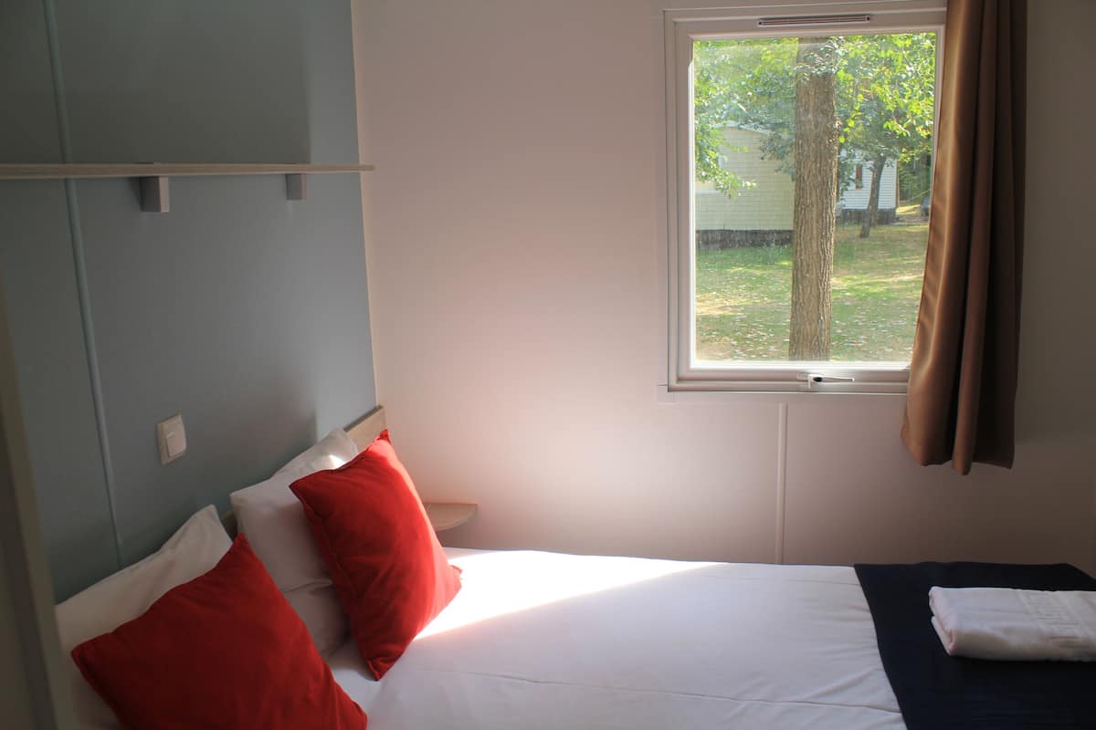 Un dormitorio con cama, ventana y vistas al exterior.