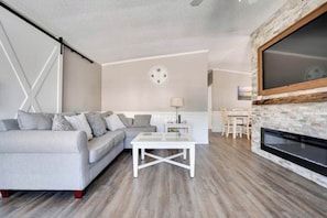 A living room with a sofa, coffee table, fireplace, and a clock on the wall.