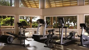 Ein Fitnessstudio mit unterschiedlichen Trainingsgeräten, darunter Laufbänder, eine Hantelbank und Kurzhanteln.
