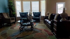 Un salon comprenant un canapé, deux fauteuils, une table basse et un tapis.