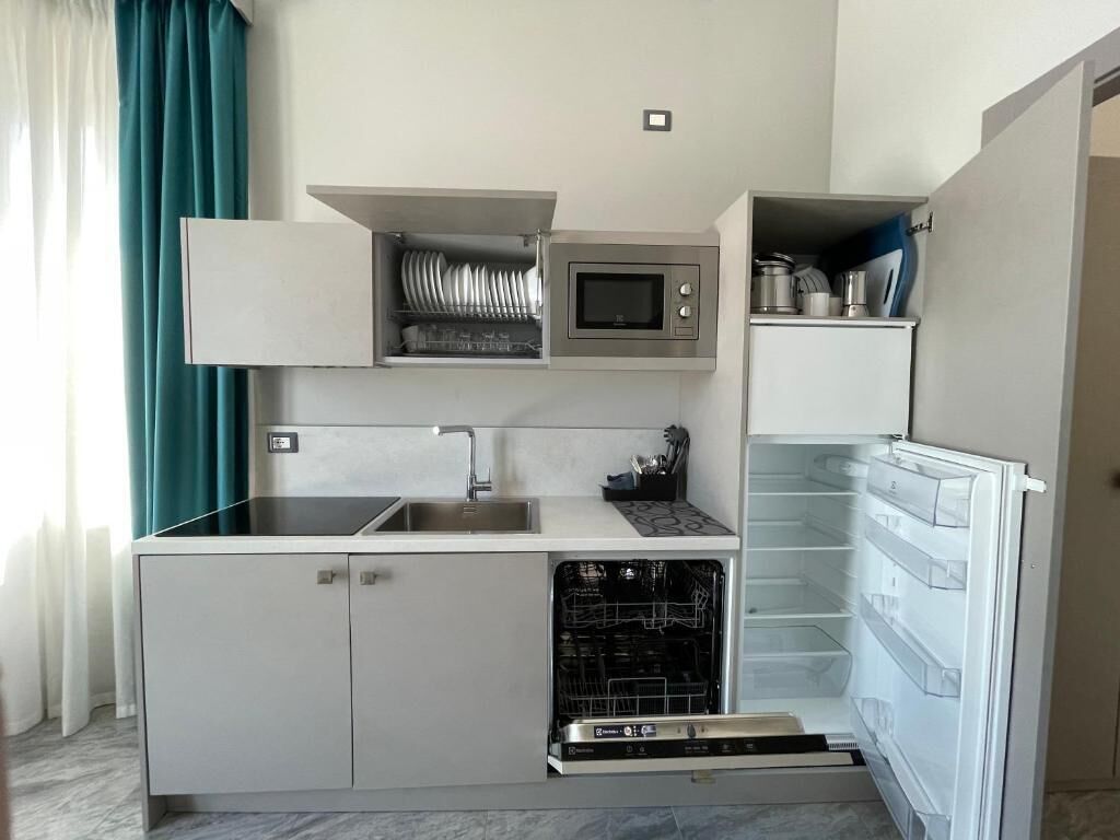 Cocina compacta con microondas integrado, lavavajillas y refrigerador.