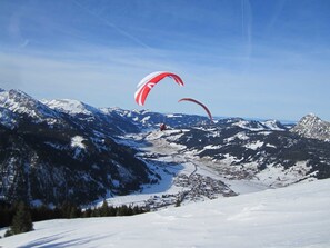 Een besneeerd berglandschap met twee paragliders.
