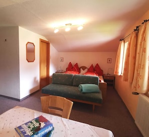 Une chambre à coucher comprenant un lit, un canapé, une chaise, une table et un radiateur.