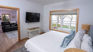 Een slaapkamer met een bed, televisie, raam, plafondventilator en bureau.