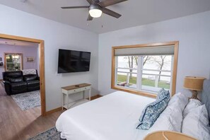 A bedroom with a bed, a TV, a window, a ceiling fan, and a desk. - Waterfront Family Retreat on Green Bay w/ kayaks (Luxemburg)