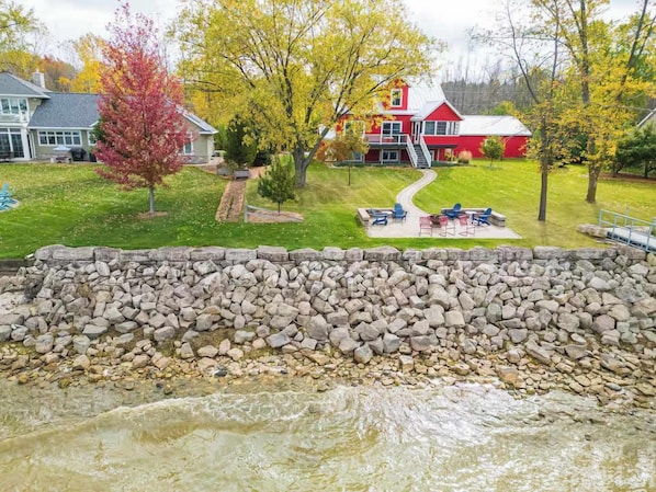 A stone retaining wall, a red house, and a grassy area with a pathway.