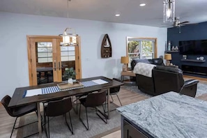 A modern living room with a dark sofa, a dining table with chairs, a TV, and a fireplace. - Waterfront Family Retreat on Green Bay w/ kayaks (Luxemburg)