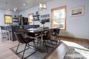 A modern kitchen with a central island, bar stools, pendant lighting, and a view of the outdoors. - Waterfront Family Retreat on Green Bay w/ kayaks (Luxemburg)