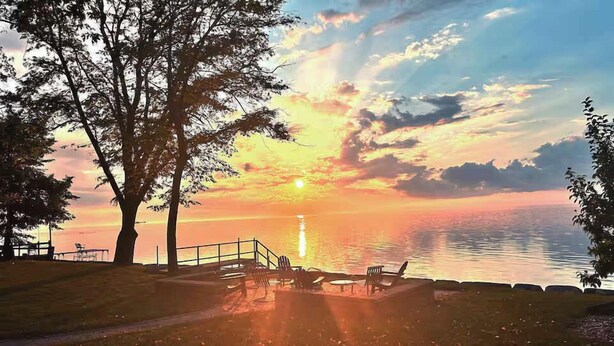 Zonsondergang bij het water met een steiger en stoelen.