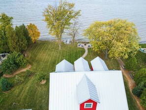 A house with a red barn, a lawn, and a view of a lake. - Waterfront Family Retreat on Green Bay w/ kayaks (Luxemburg)
