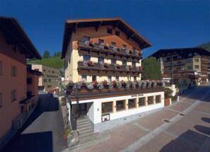 Et hotel med flere etager, altaner, en restaurant i stueplan og en klar himmel.
