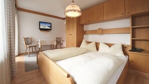 A hotel room with two beds, a television, wooden furniture, and a desk.