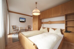 Habitación de hotel con dos camas, televisión, muebles de madera y un escritorio.