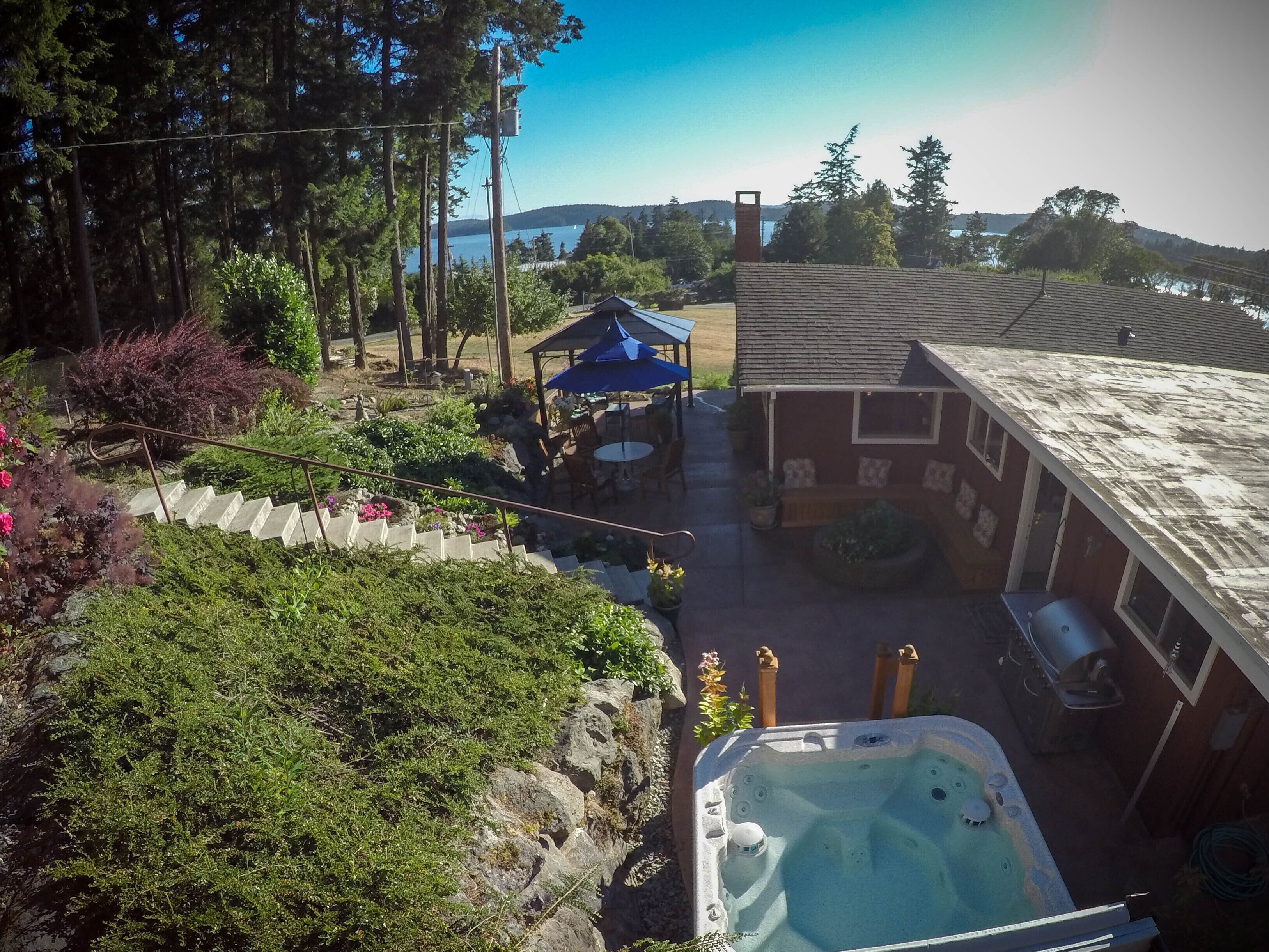 A backyard with a hot tub, a covered patio, and a wooden deck.