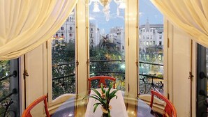 A room with a balcony, a table, chairs, and a chandelier.