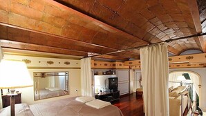 A hotel room with a large bed, a desk, a mirror, a television, and a red carpet.
