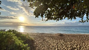 A beach with a boat in the water, trees, and the sun setting over the horizon. - Family Vacation Home - Ocean Views - Walk to Beach - Sleeps 7 - Hosted by Owner (Lahaina)