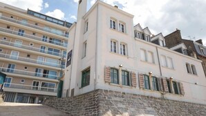 Ein mehrgeschossiges Gebäude mit Balkonen, einem Steinsockel und einer Mischung aus moderner und traditioneller Architektur.