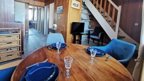 Ein Essbereich mit einem Holztisch, gedeckt für vier Personen, einer Treppe und Blick in den angrenzenden Raum.