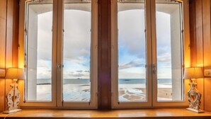 Ein Zimmer mit großem Fenster und Blick auf einen Strand.