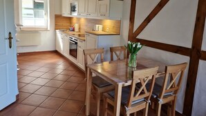 A kitchen with white cabinets, a wooden table, and chairs. - E - Uns Schün, Germany (Middelhagen)