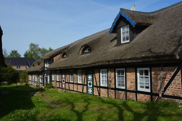 A traditional half-timbered house with a thatched roof and a small garden in front. - E - Uns Schün, Germany (Middelhagen)