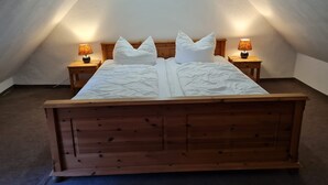 A bedroom with a wooden bed, two bedside tables with lamps, and a skylight. - E - Uns Schün, Germany (Middelhagen)