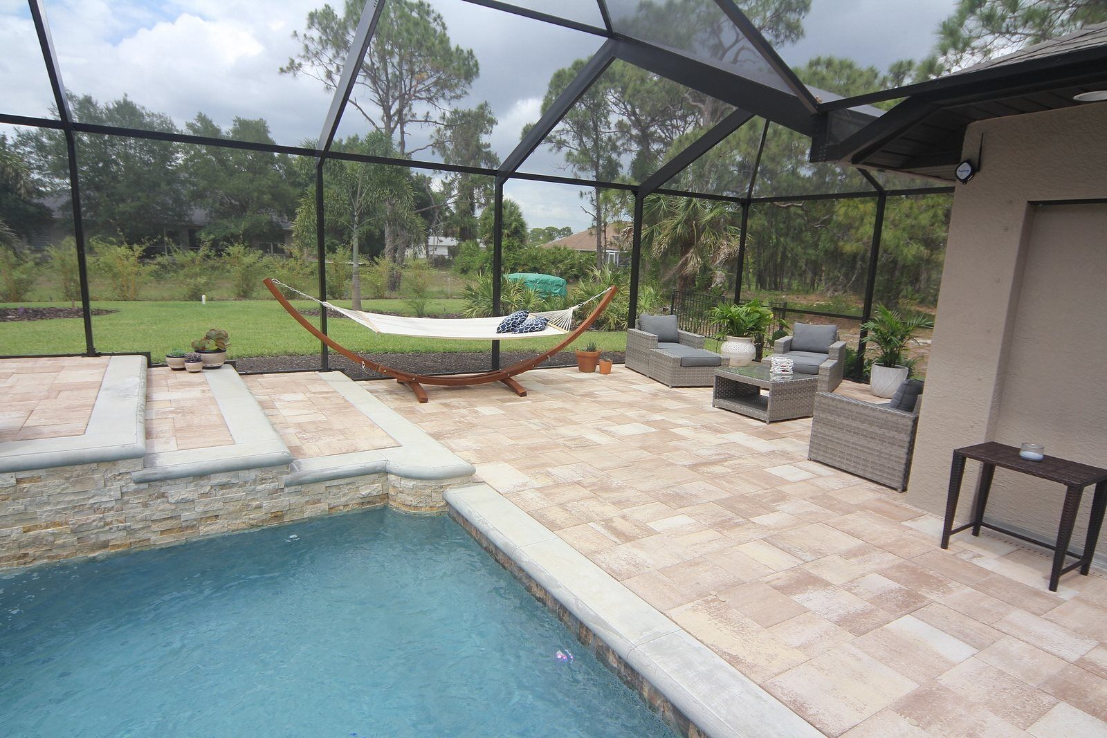 A pool area with a hammock, outdoor furniture, and a view of the surrounding landscape.